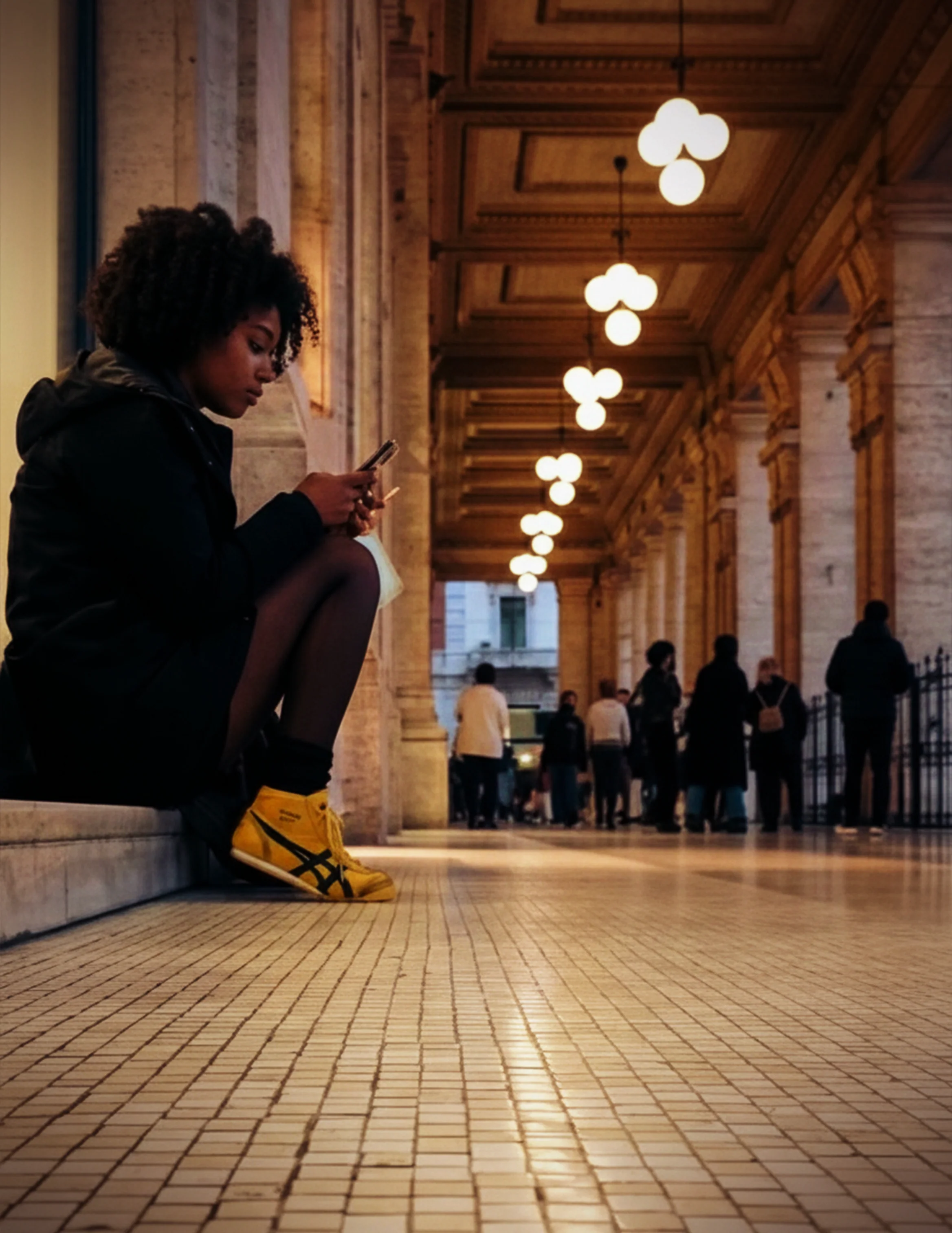 Woman wearing yellow and black Onitsuka Tiger Mexico 66 sneakers in an ornate indoor corridor