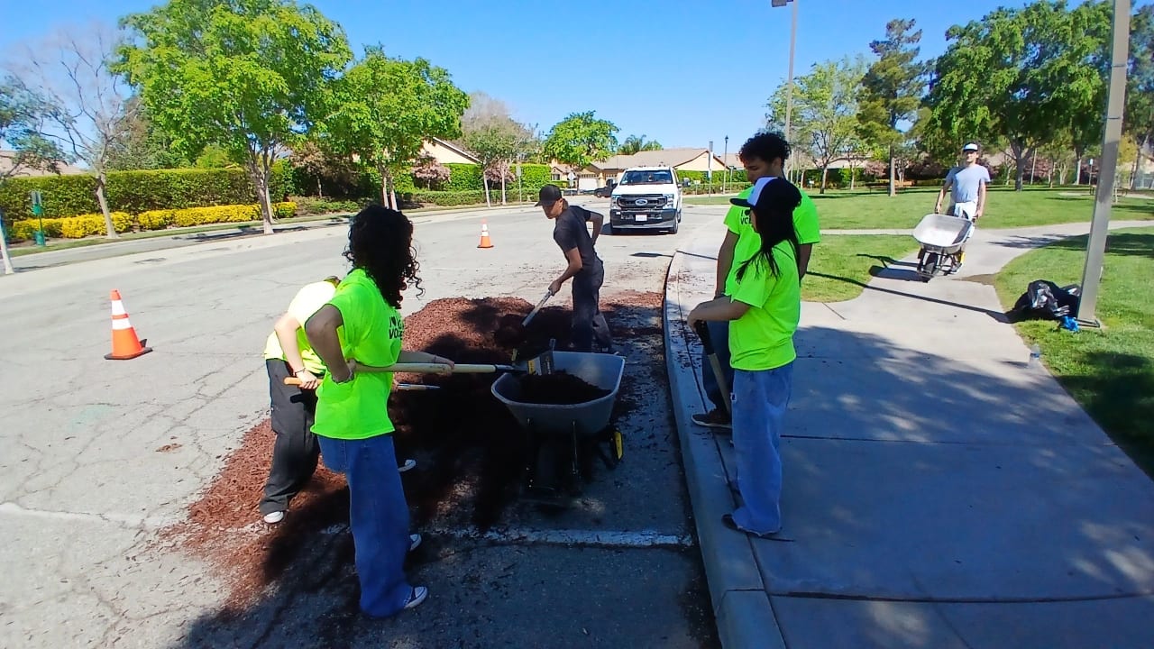 Beaumont Interact students in safety vests spreading mulch as part of a neighborhood service project