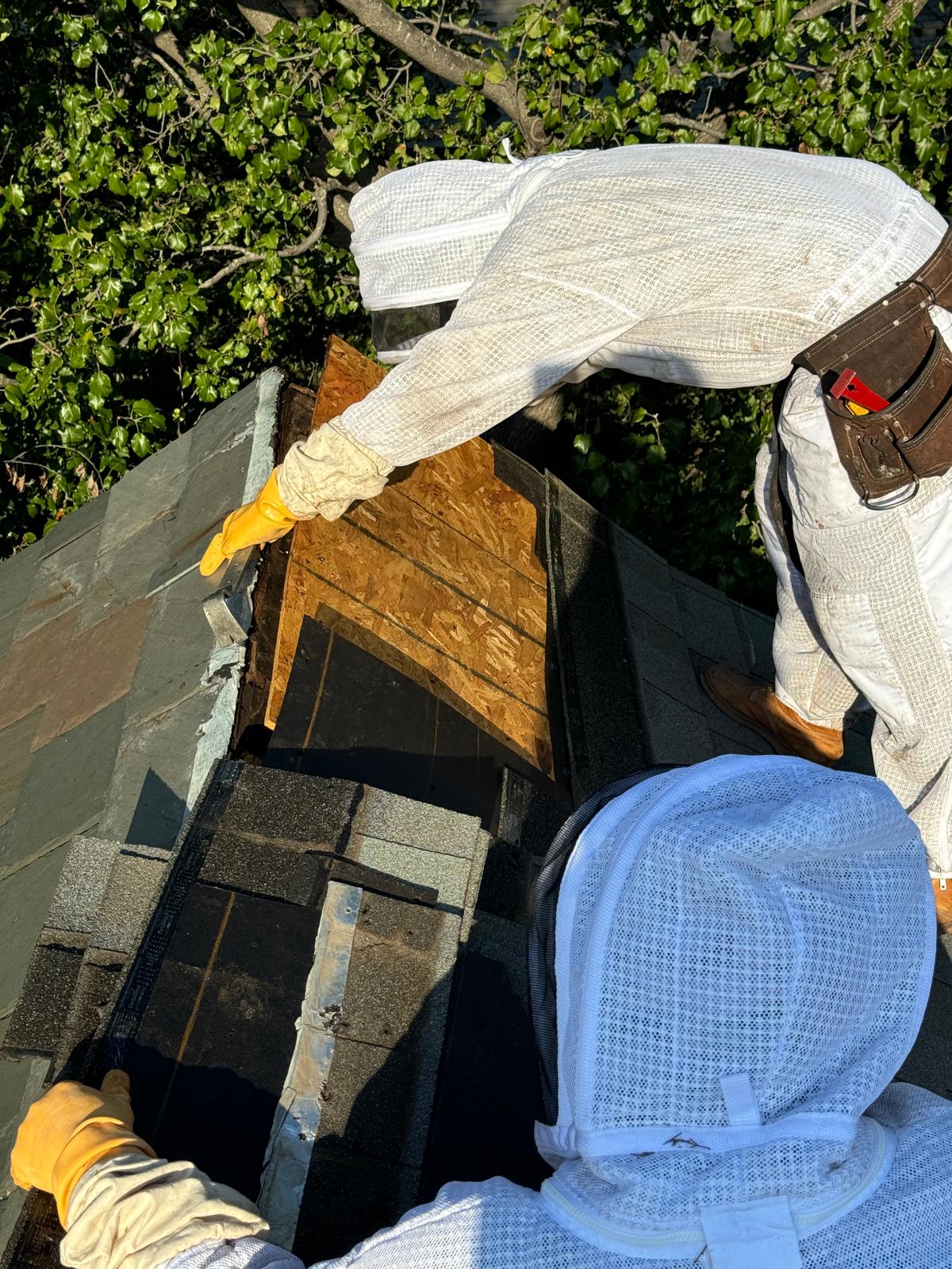 Two workers in protective suits lifting a section of the roof.
