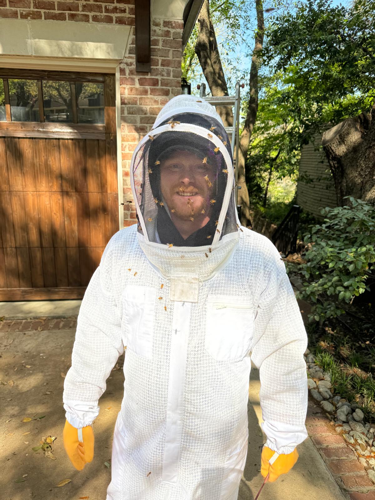 Beekeeper in protective suit with bees on it.