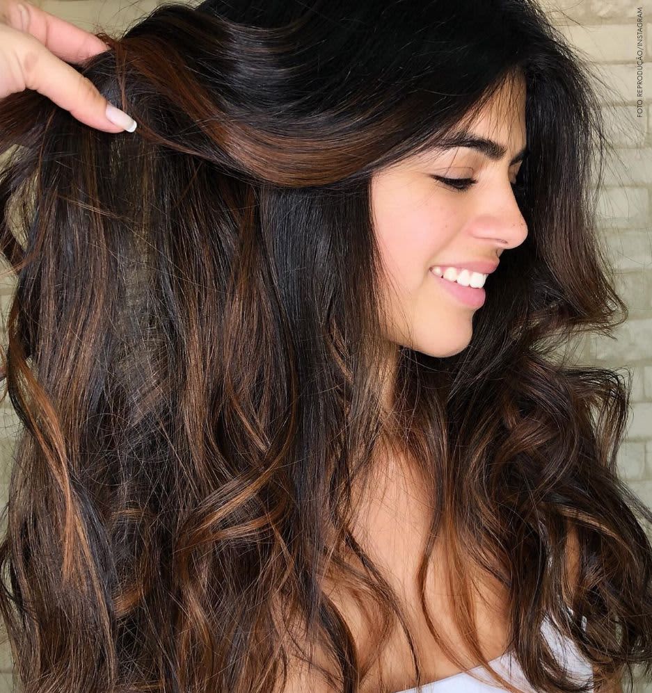 Mulher com cabelo escuro cacheado em um vestido de verão na cidade