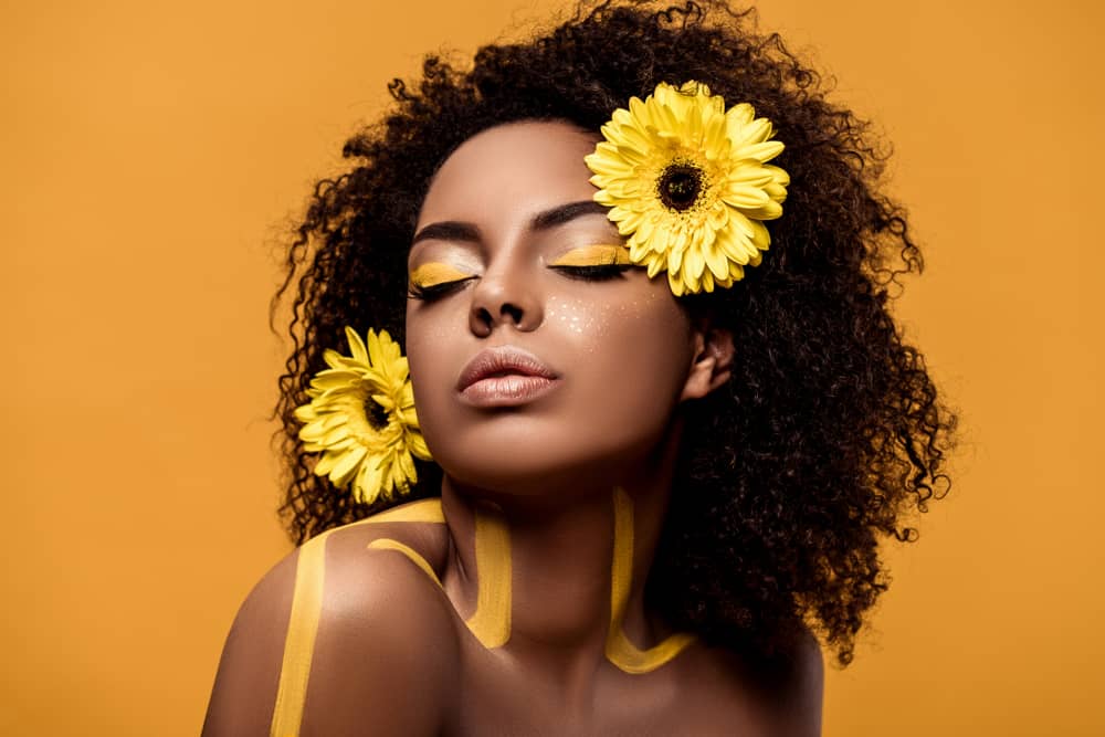 Mulher maquiada com delineador amarelo e acessórios de girassol