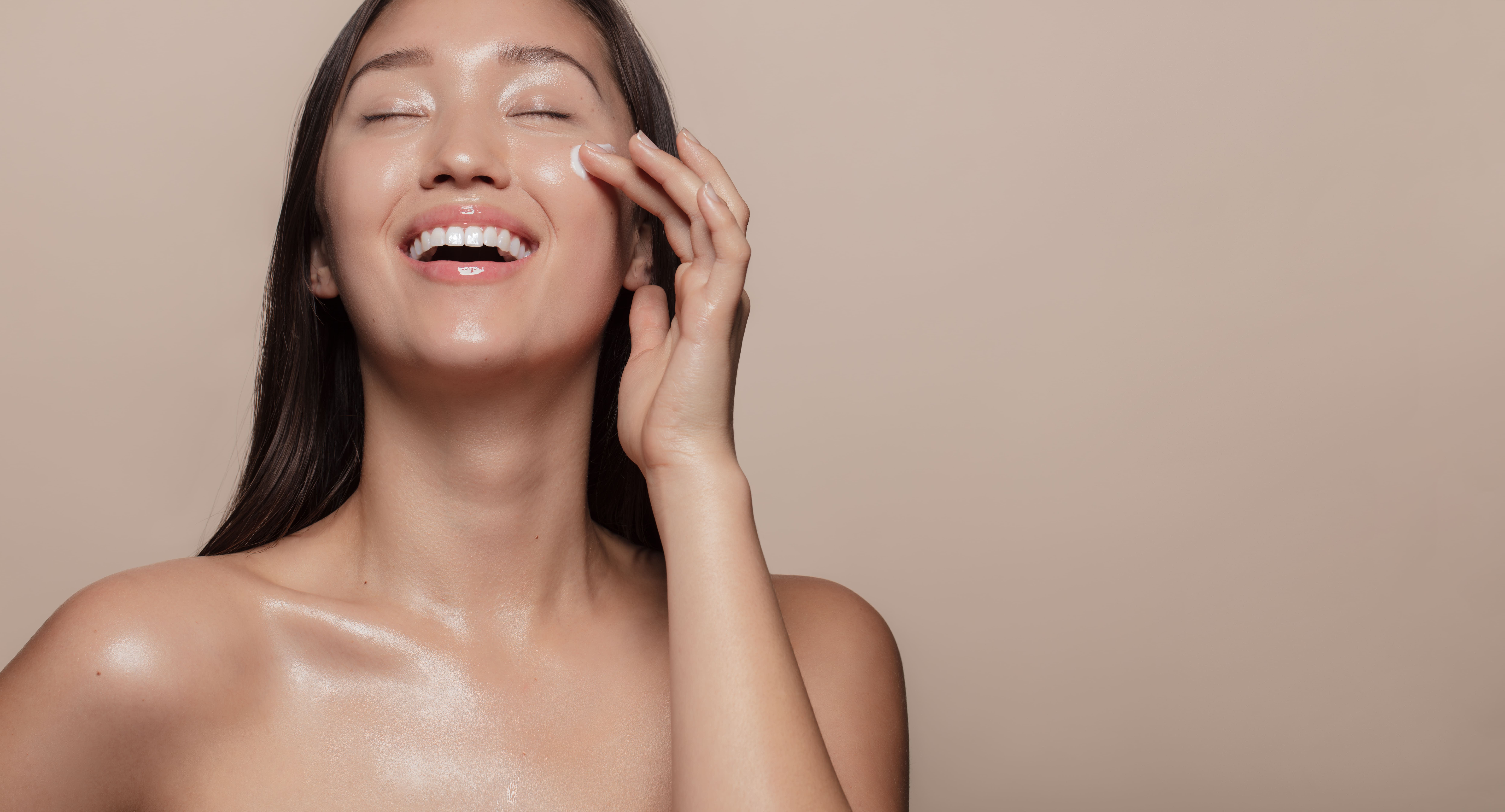 Imagem de mulher coreana sorrindo fazendo skincare