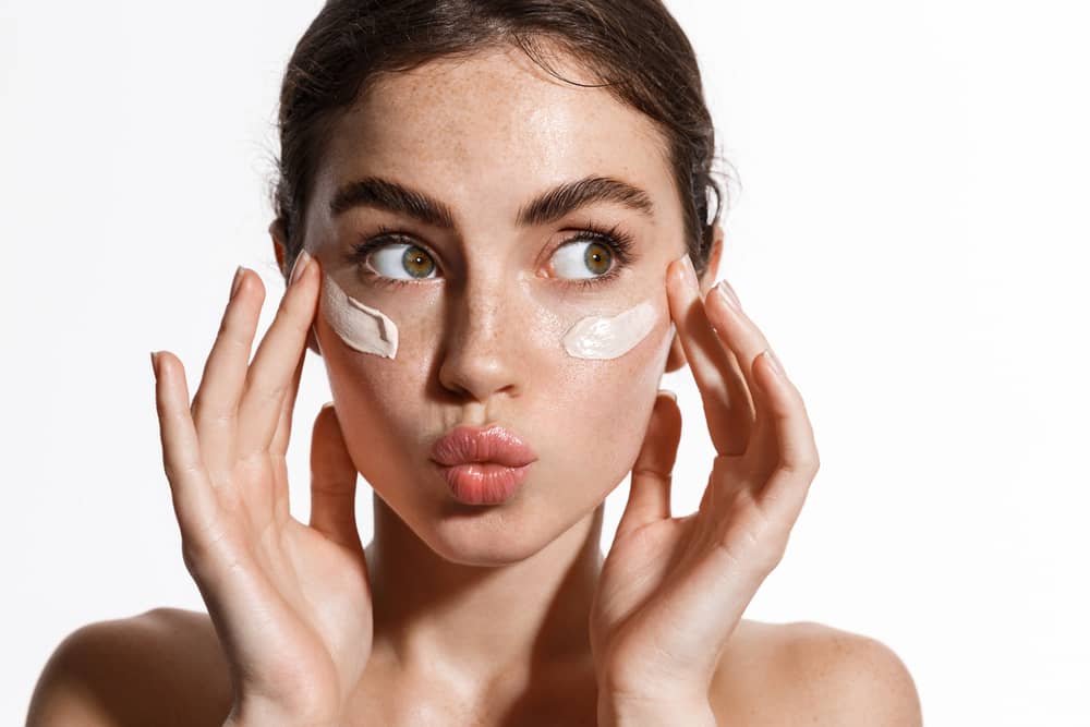 Imagem de muher aplicando creme facial na pele
