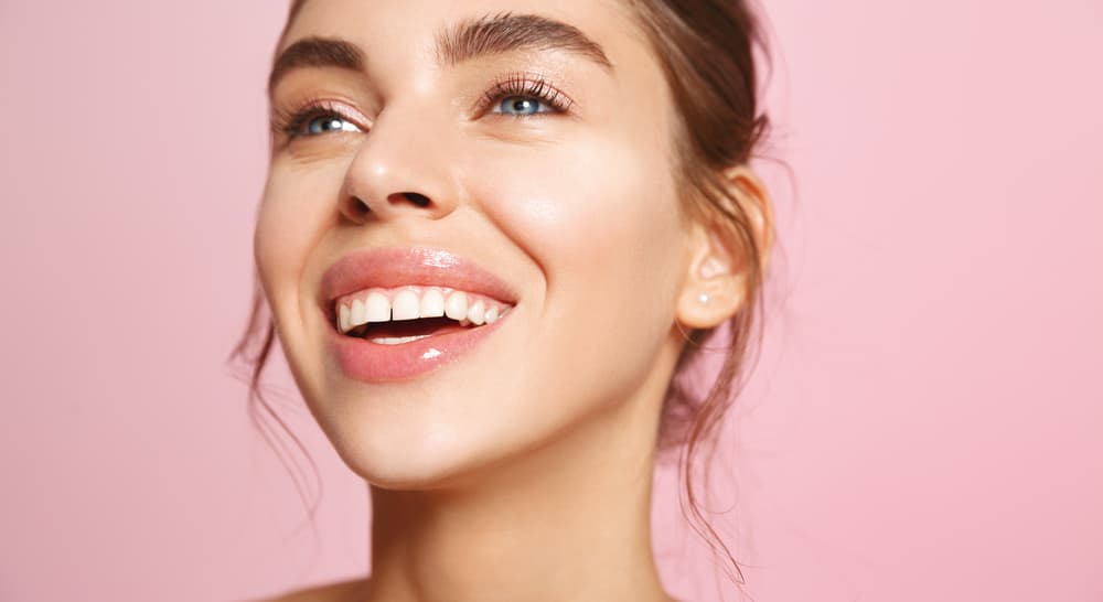 Maquiagem com pele iluminada, gloss nos lábios e acabamento natural