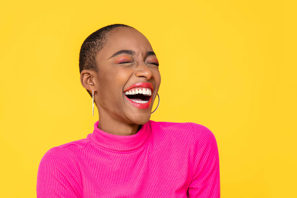 Imagem de mulher sorridente com maquiagem colorida