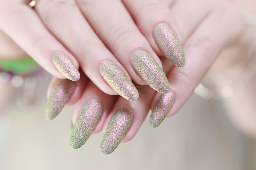 Imagem de unhas pintadas com esmalte glitter em tom dourado