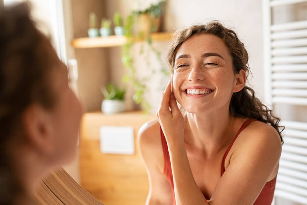 Imagem de mulher se olhando no espelho durante o skincare