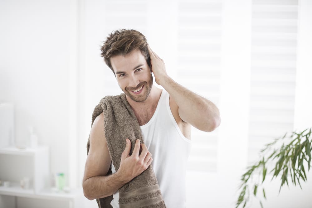 Imagem de homem com toalha nos ombros e com as mãos no cabelo