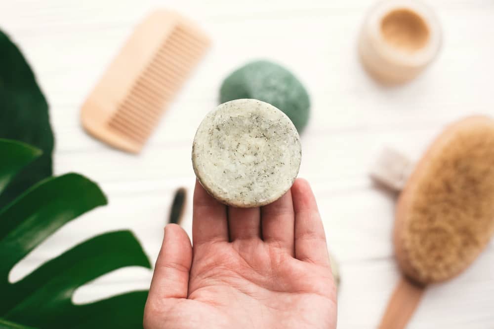 A imagem mostra uma mão segurando um item de cosmético em barra