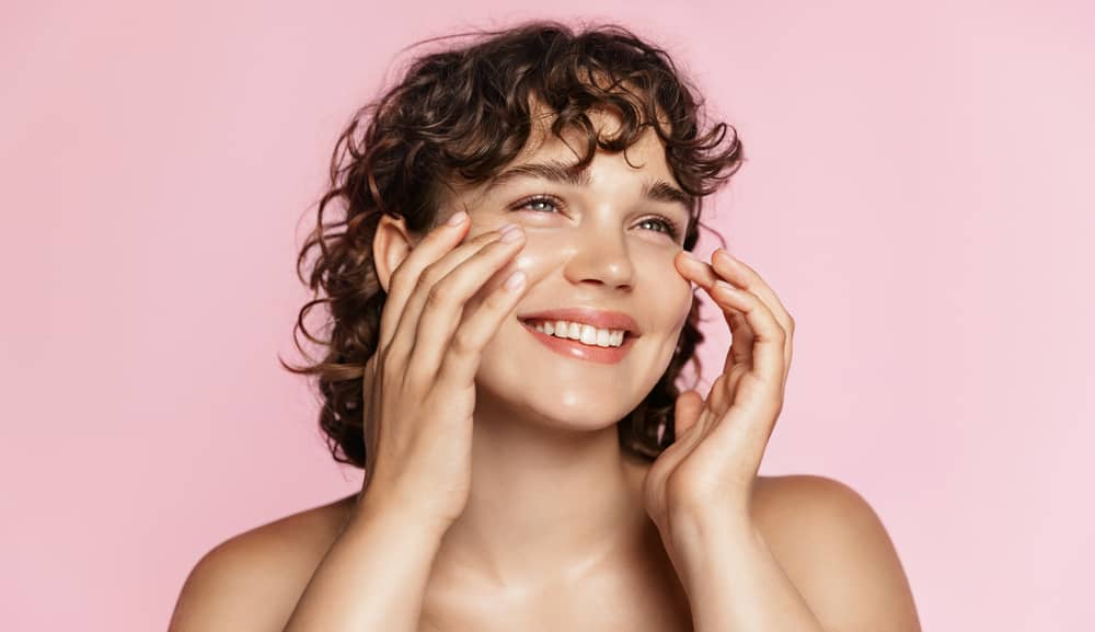 Imagem de mulher sorrindo, ela tem uma pele radiante e hidratada