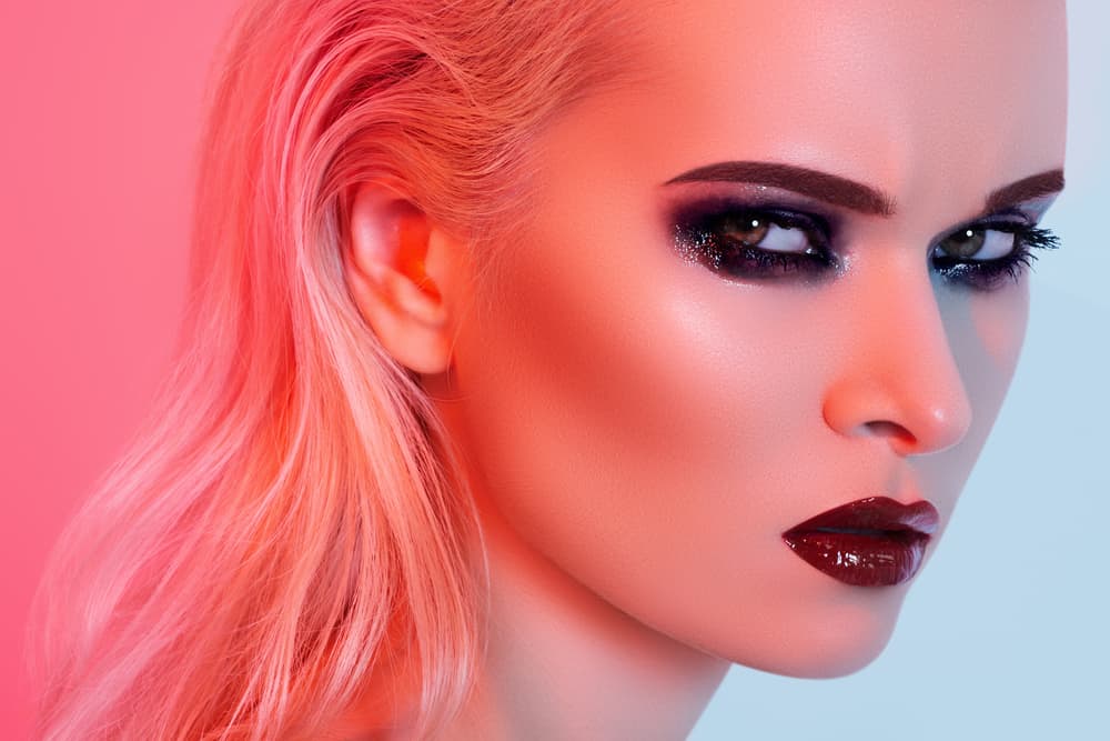 Na imagem a modelo está usando maquiagem com sombre preta esfumada e batom vermelho com efeito vinil