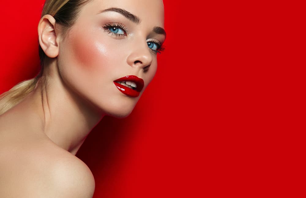 Imagem de mulher maquiada com pele glow e batom efeito vinil