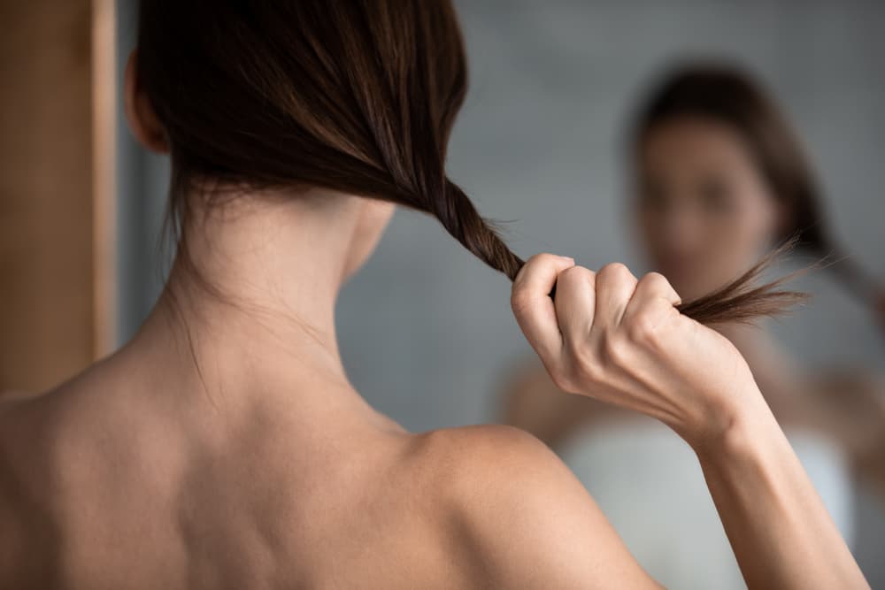 Imagem de mulher em frente ao espelho olhando para o comprimento do seu cabelo