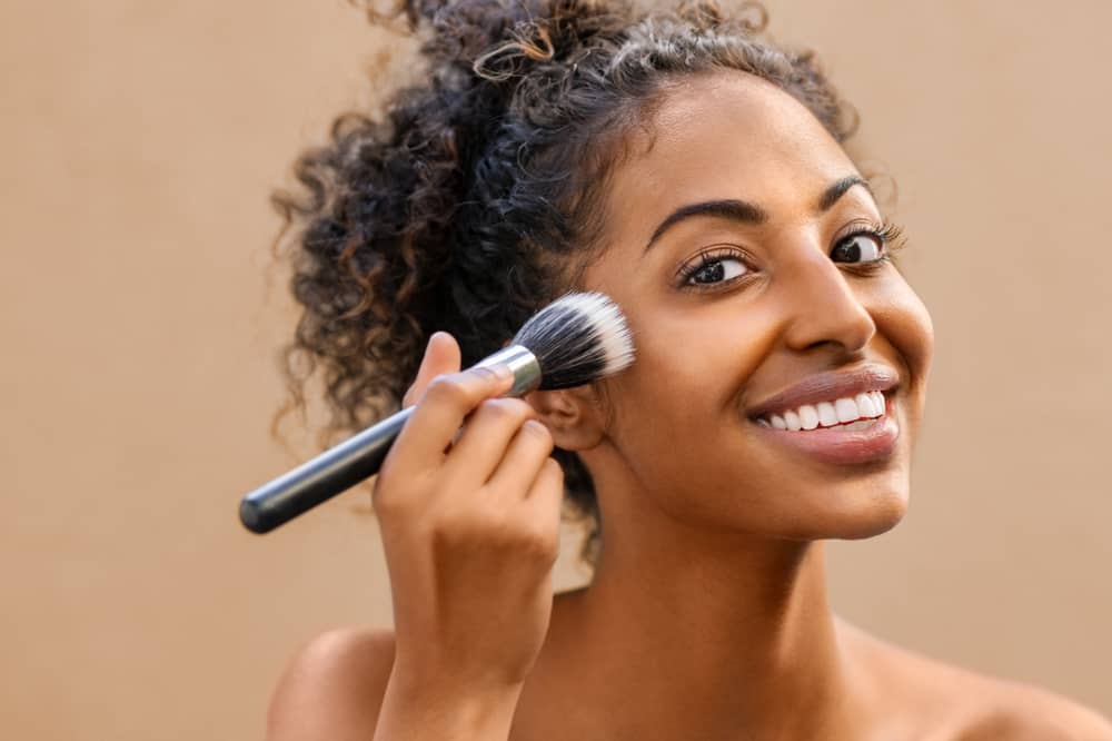 Mulher aplicando blush com pincel de maquiagem