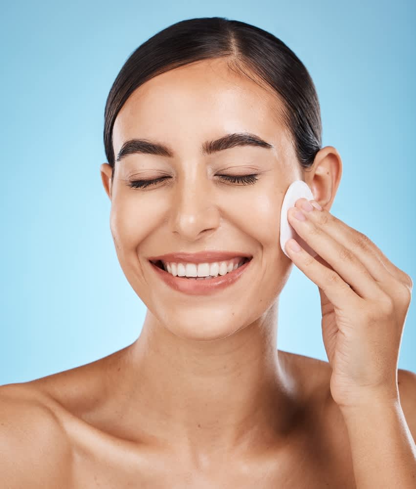 Mulher sorrindo enquanto faz sua rotina de skincare
