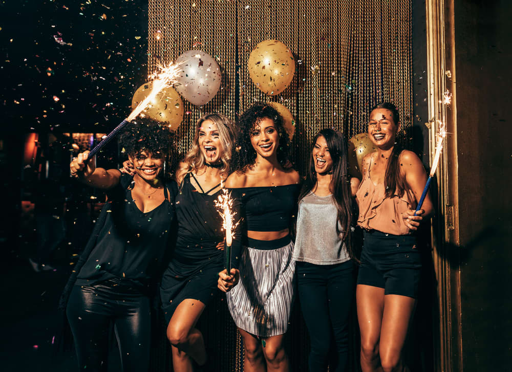 Imagem com um grupo de mulheres maquiadas celebrando em uma festa noturna
