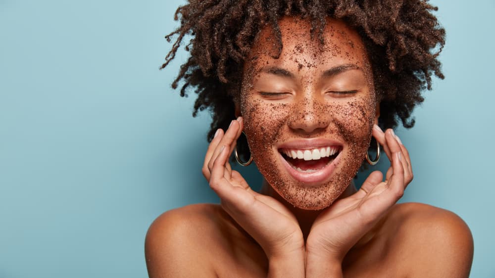Imagem de mulher sorrindo enquanto esfolia a pele