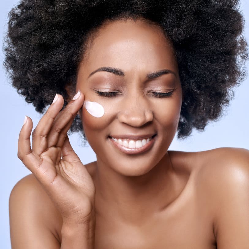 Mulher aplicando creme facial na pele em uma rotina de skincare