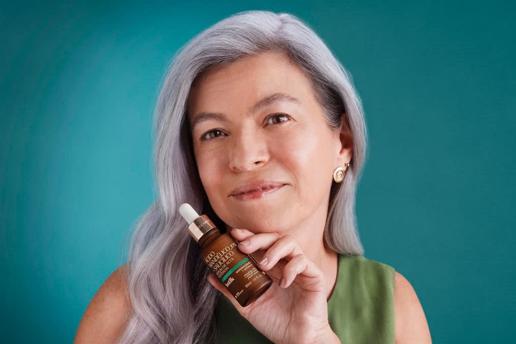 Mulher de cabelo branco segurando um sérum da linha Botik Mandélico