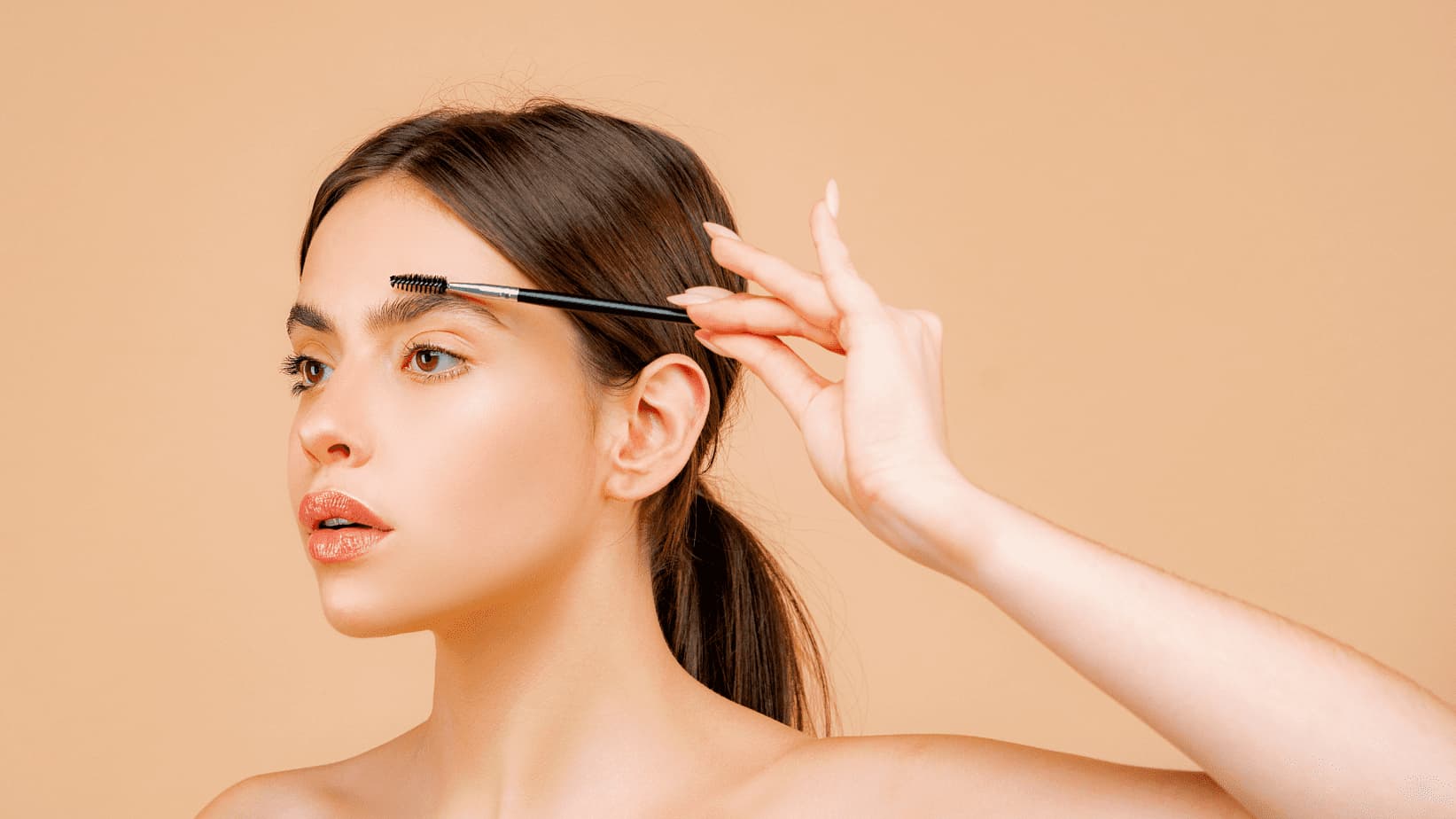 Imagem de mulher maquiagem penteando a sobrancelha com uma escova de maquiagem