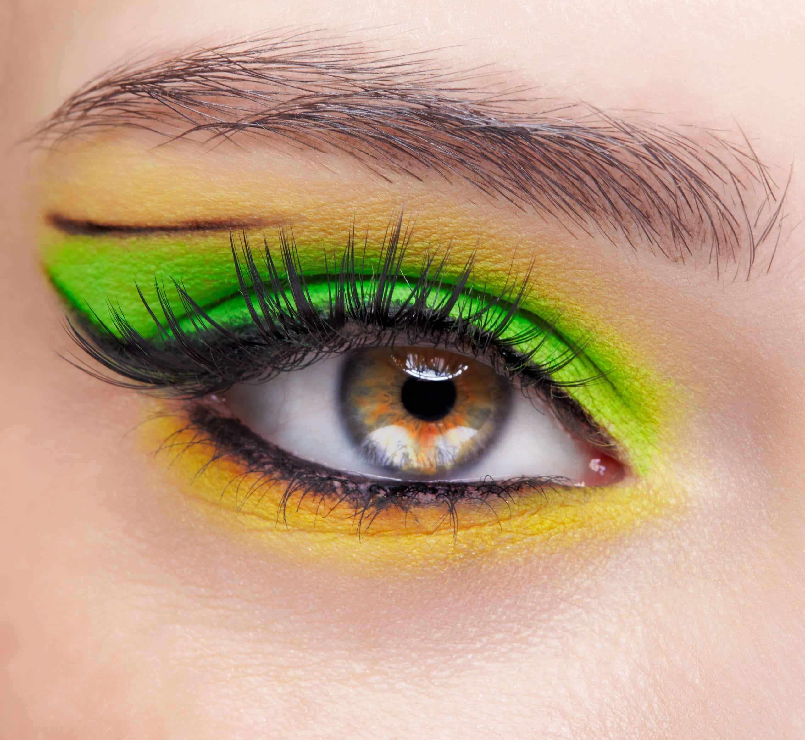 Imagem de maquiagem colorida com sombra nas cores verde e amarelo e delineado e lápis de olho na cor preta
