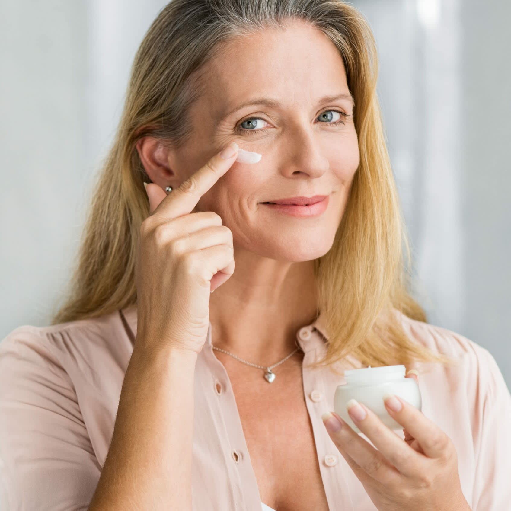 Imagem de mulher aplicando creme no rosto