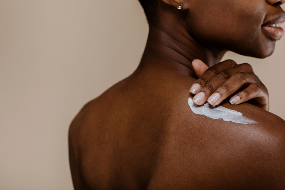 Imagem de mulher aplicando hidratante na pele