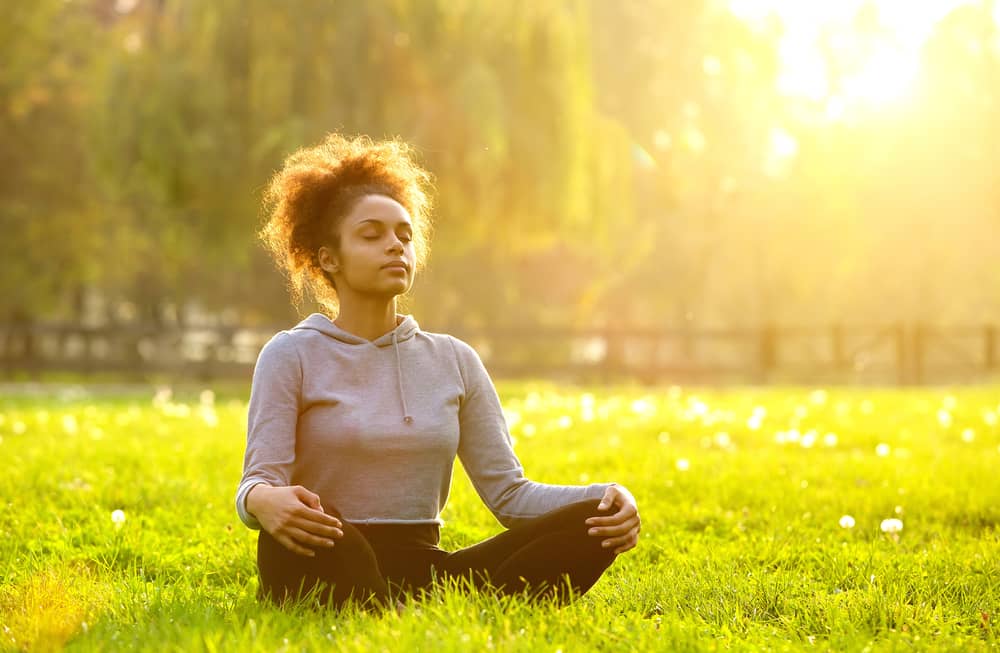 Imagem de mulher meditando ao ar livre