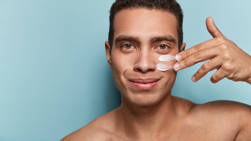 Imagem de homem aplicando um produto de skincare no rosto