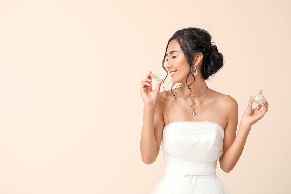 Imagem de mulher com vestido de noiva sentindo o cheiro de um perfume