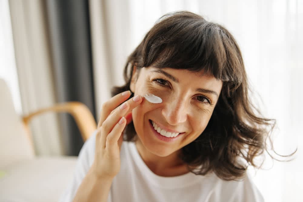 Imagem de mulher aplicando creme na pele