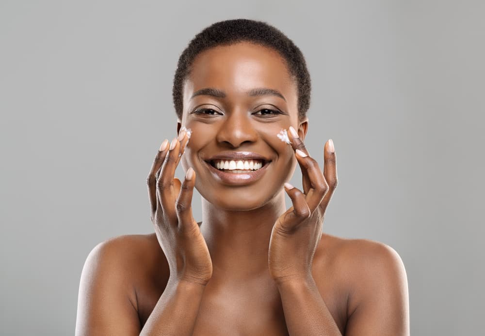 Imagem de mulher aplicando creme na pele.
