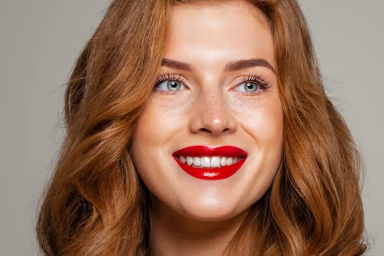 Mulher ruiva maquiada com batom vermelho