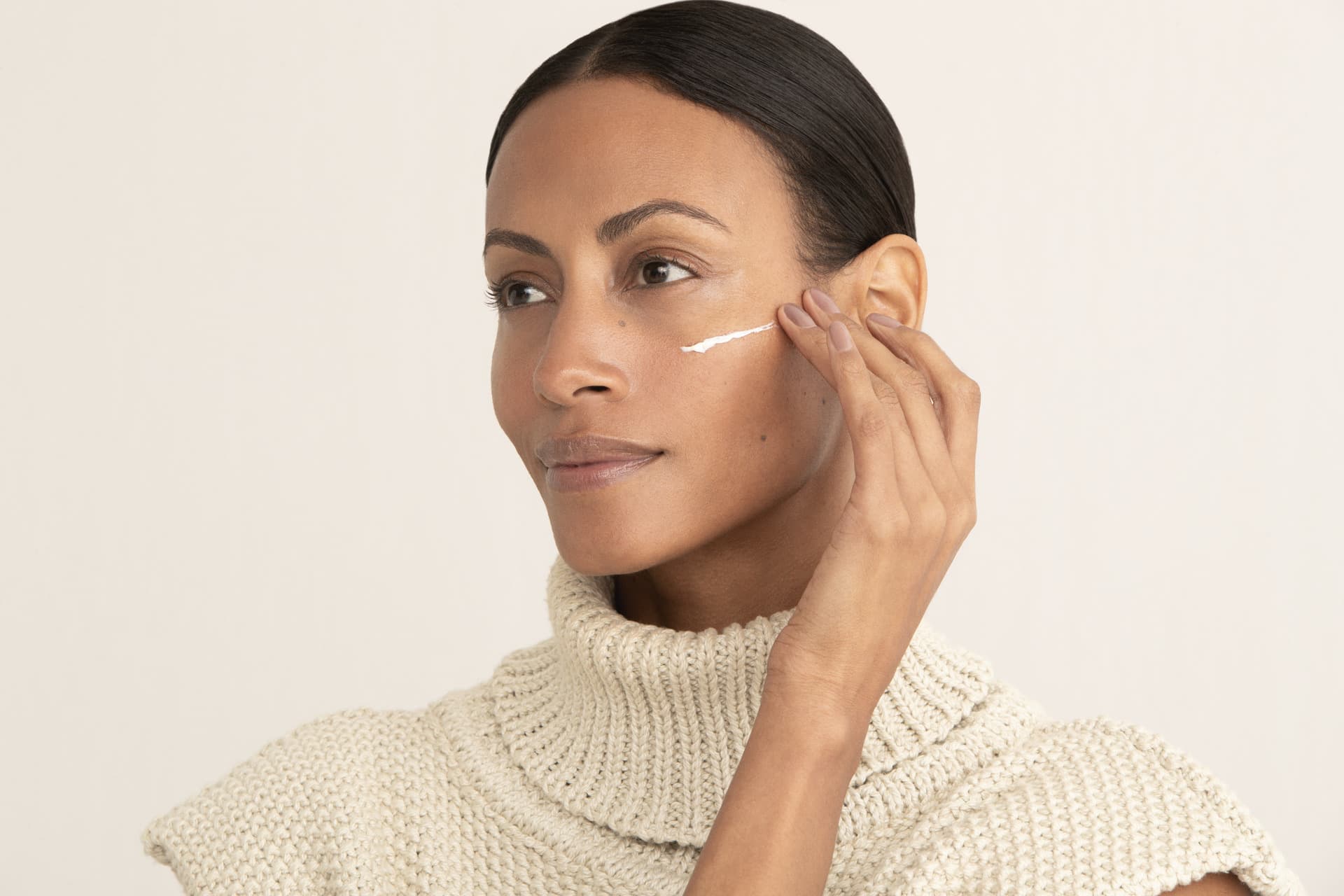 Imagem de mulher aplicando creme facial na pele