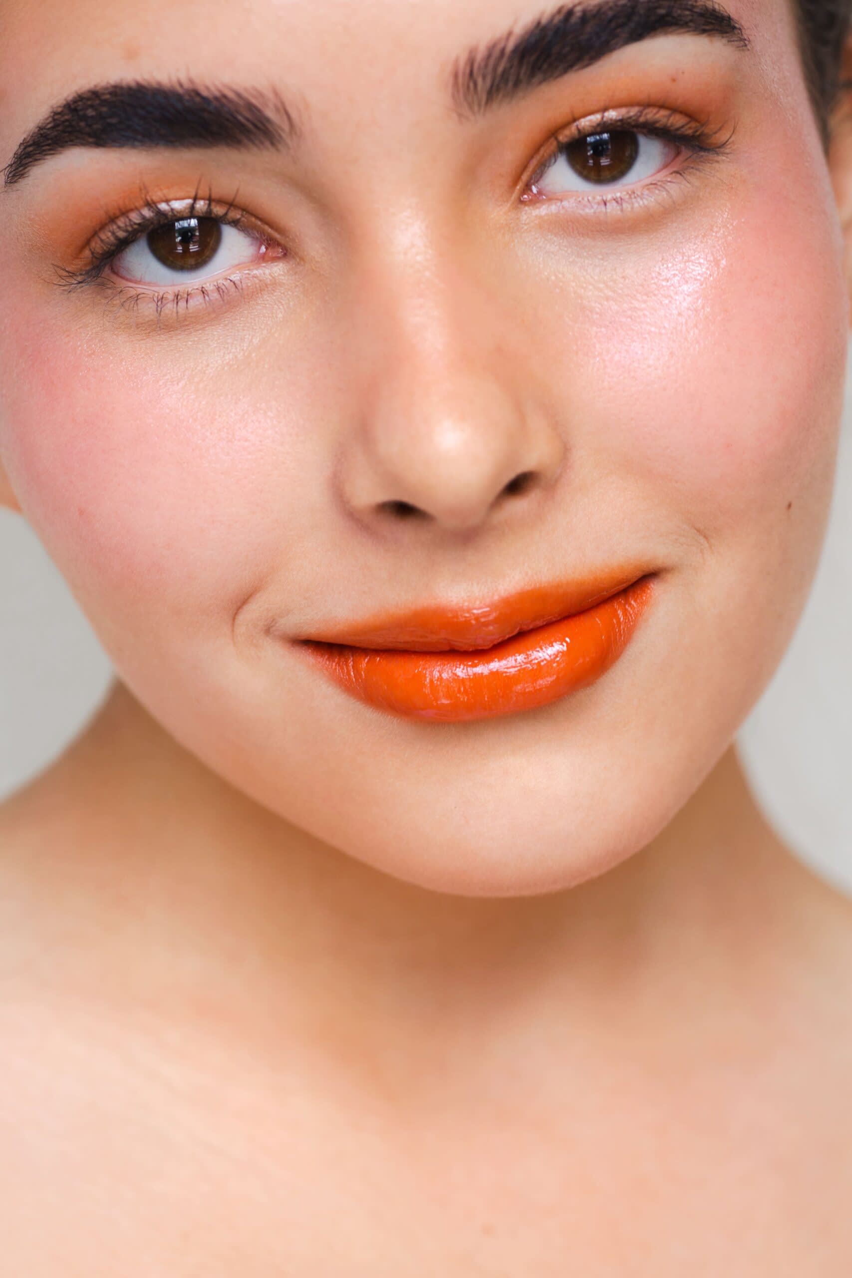 Mulher usando blush e maquiagem completa em tons alaranjados