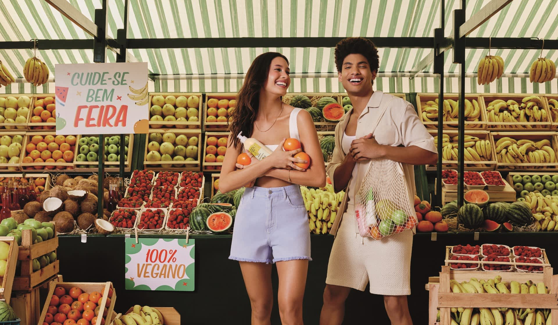 Casal em feira segurando sacolas que contém frutas e itens de Cuide-se Bem