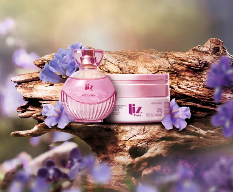 Frasco e embalagem dafragrância de Liz Flora e creme corporal, ao fundo o cenário com madeira e flor de Jacarandá