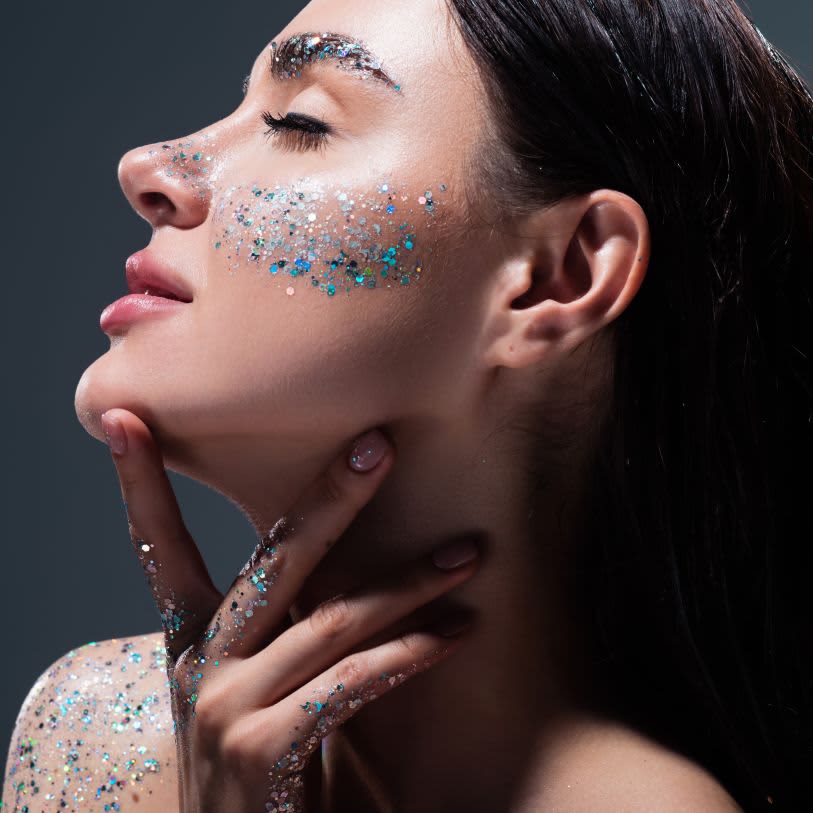 Mulher usando glitter azul no rosto e corpo