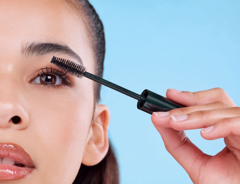 Mulher aplicando sérum para cílios e sobrancelhas nos olhos