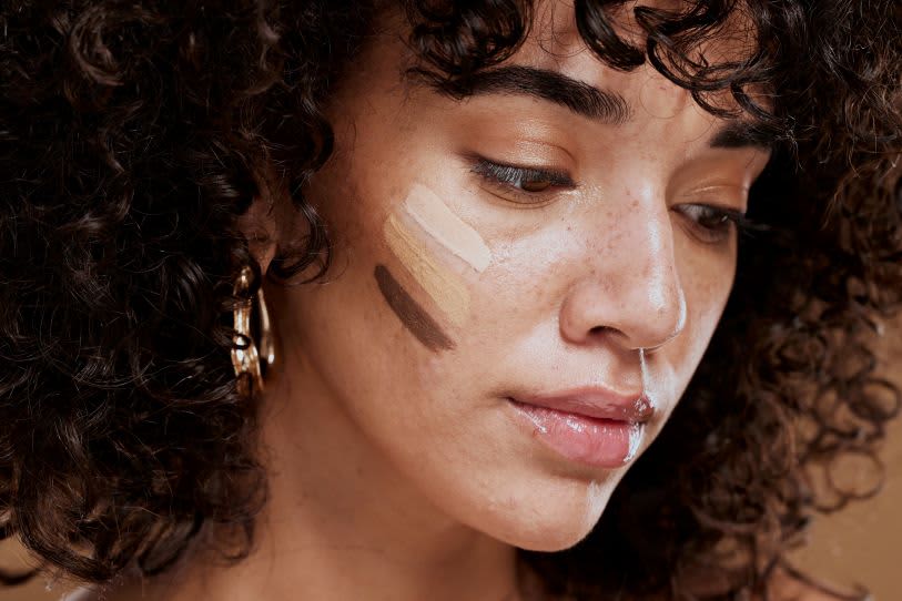 Mulher com cabelo cacheado testando cores de maquiagem