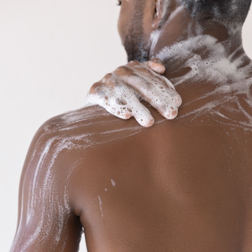 Foco em costas de um homem ensaboadas com sabonete masculino.