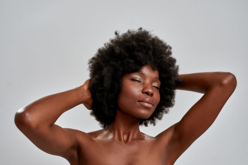 Mulher negra com um poderoso cabelo crespo e olhos fechados, transmitindo paz e orgulho em uma composição minimalista e elegante.