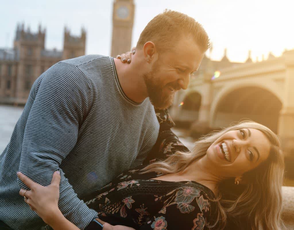 Casal de homem e mulher felizes em um cenário de por do sol em Londres.