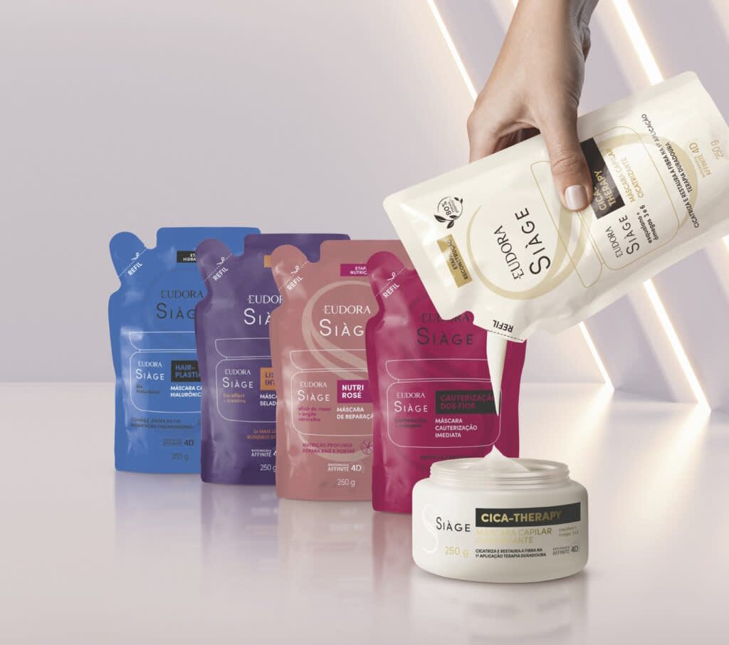 Todos os refis de máscara capilar de Siàge enfileirados, temos 5 na foto. Um deles está abastecendo o pote de máscara capilar.