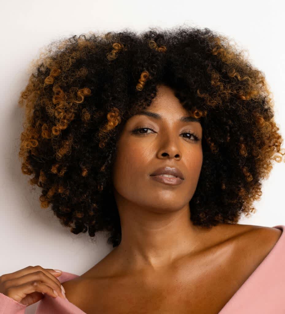 Mulher de cabelo cacheado médio com blusa rosa