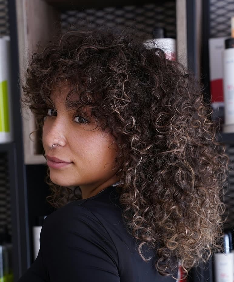 mulher de cabelo cacheado médio com franja