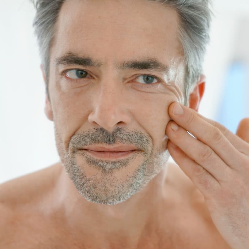 Homem de cabelo grisalho cuidando da barba