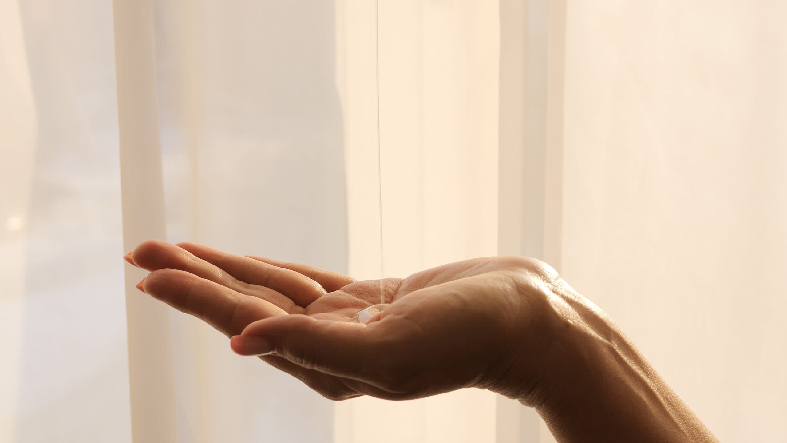  óleo cosmético é derramado na palma da mão da mulher, revelando sua textura e propriedades nutritivas. Sinta a maciez sedosa do óleo enquanto ele rejuvenesce e hidrata, deixando a pele radiante e revigorada.