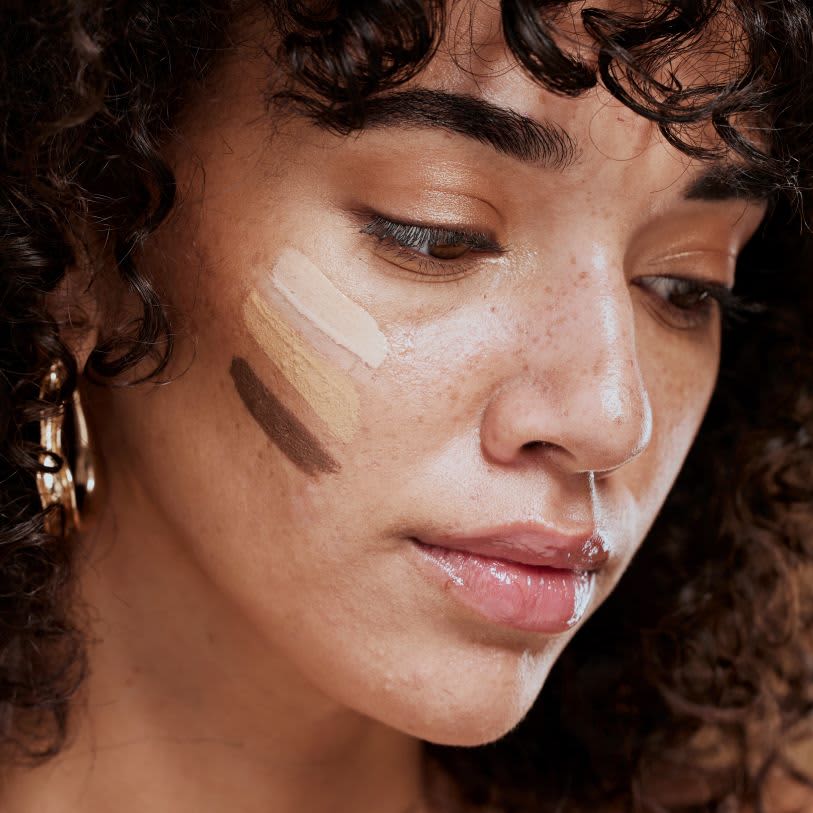 Mulher usando diferentes cores de corretivo no rosto